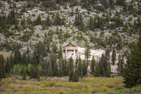 Log cabin home built into the side of a steep cliff on a river in Montana, USA.の写真素材