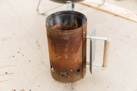 Rusty old chimney starter for igniting charcoal briquettes.の写真素材