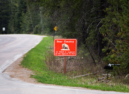 Bright red ''Bear Country'' sign posted near the entrance of Glacier National Park in Montana, USA.の写真素材