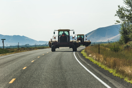 Heavy farm equipment driving down a rural highway.の写真素材