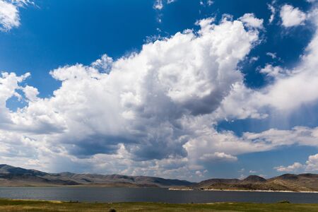 Puffy cumulus clouds in blue sky over a lake in western Montana, USA.の写真素材