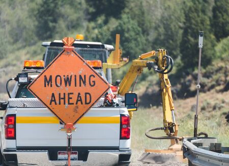 Work truck on highway with ''Mowing Ahead'' sign on back.の写真素材