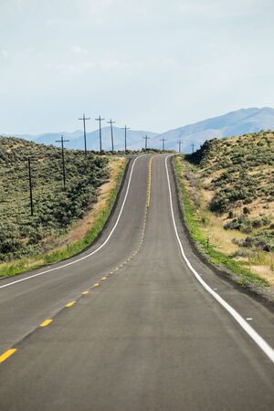 Empty desert highway with mountains in background. Southern Idaho, USA.の写真素材