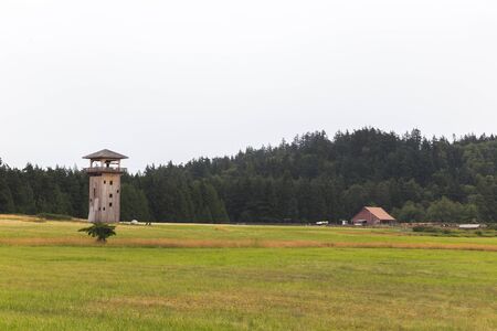 Wooden fort structure and out buildings with field and forest. Summer camp property in lush forested area.の写真素材