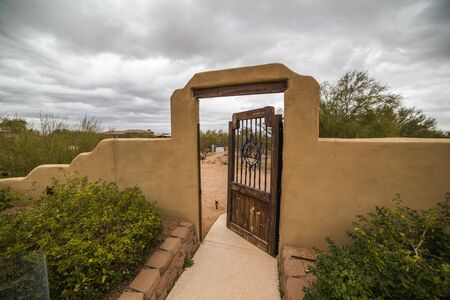 Storm clouds over stucco wall with wood and steel door or gate. Scottsdale, Arizona, USA.の写真素材