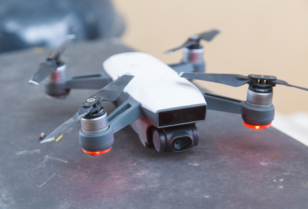 Photography drone with four propellers parked with red lights lit up underneath propellers.の写真素材