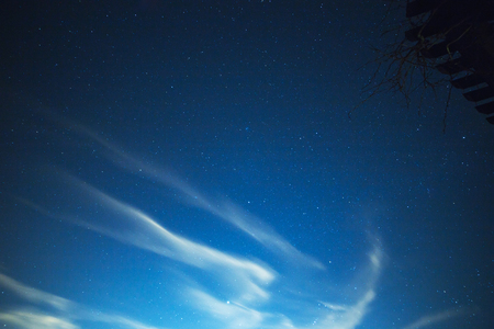 Soft clouds drifting in a night sky with stars above.の写真素材