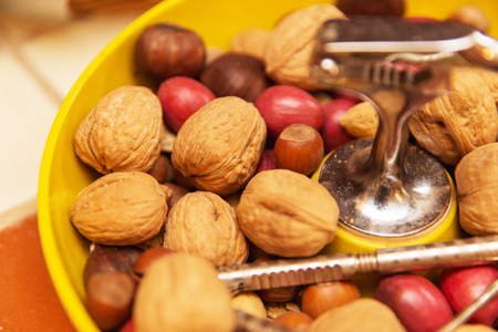 Walnuts and chestnuts in a bowl with cracking tools or utinsels.の写真素材
