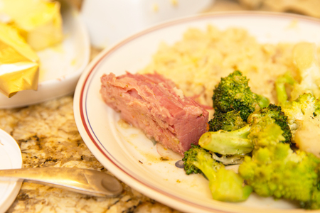 Ceramic plate with corned beef, broccoli, and rice in a kitchen setting.の写真素材