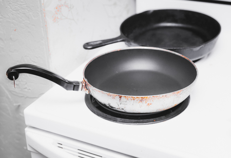 Nonstick pan and cast iron pan on  a white oven with electric coil burners.の写真素材
