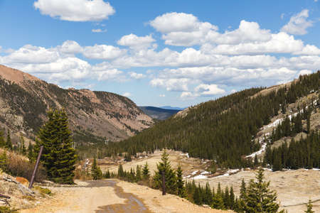 Expansive view of high desert mountains, blue sky, and clouds. Beautiful summer day in rugged mountain area. Vast open view of Rocky Mountains in the United States.の写真素材