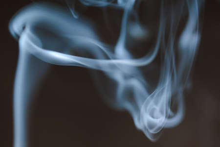 Smoke clouds swirling in blue light against a dark background.の写真素材