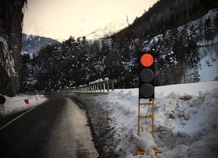 Mountains: red traffic light for avalanche, snowy weather, ice on streetの写真素材