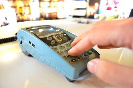 Closeup of hand typing payment details on POS machine in a storeの写真素材