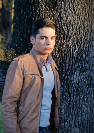 Portrait of handsome young man with leather jacket and treeの写真素材