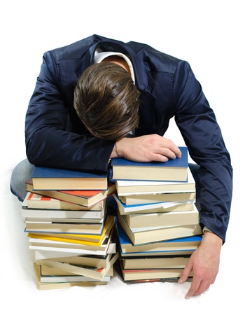 Young student sleeping on piles of books, isolated on whiteの写真素材
