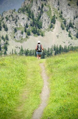 Woman or girl walking in the mountains with backpack, healthy trekkingの写真素材