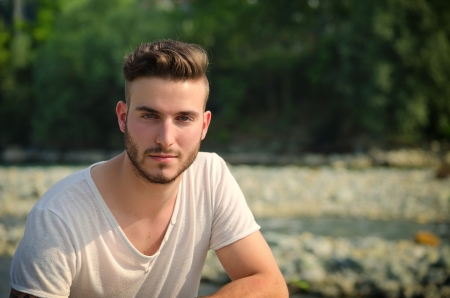 Portrait of handsome young man in white t-shirt outdoors, looking in cameraの写真素材