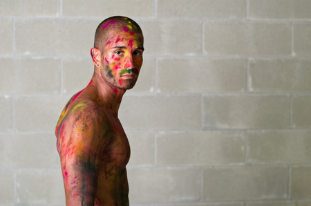 Handsome young man with skin painted all over with bright Holi colorsの写真素材