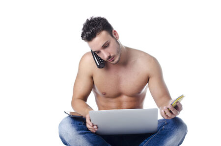 Shirtless muscular young man overwhelmed by technology, using laptop computer, PC tablet, phonesの写真素材