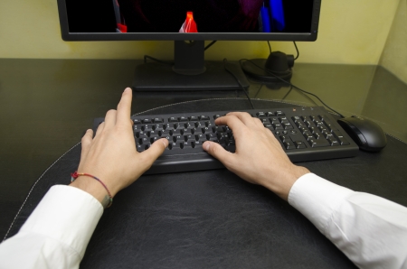Self point of view of male hands typing on computer keyboard, screen partially visibleの写真素材
