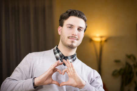 Handsome young man making heart sign with his hands and fingersの写真素材