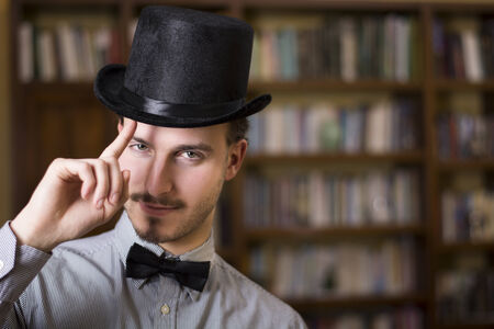 Attractive young man wearing top hat and bow tie, looking at camera. Indoors shotの写真素材