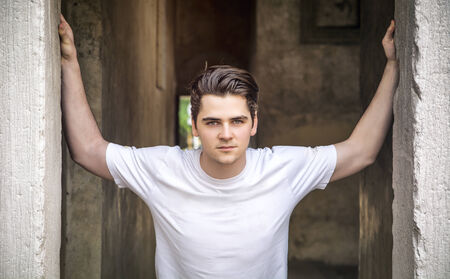 Young man with arms open on threshold, with confident look の写真素材