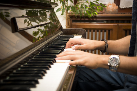 Male hands playing piano indoors inside houseの写真素材
