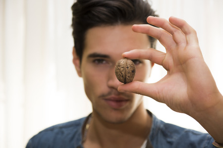 Young man holding a large delicious nut in his hand, focus to the fruit