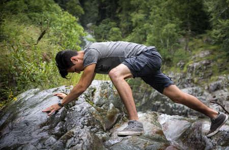 Side View of Man Clambering Over Rocky Terrain