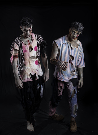 Two male zombies standing on black background walking towards cameraの写真素材