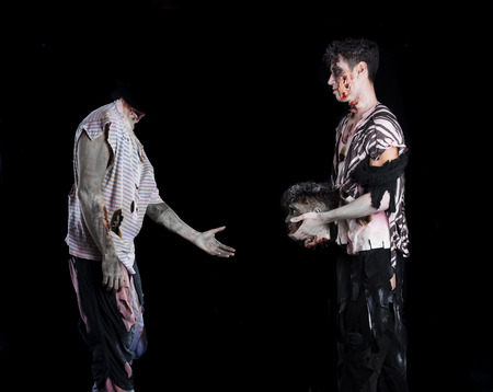 Two male zombies, one giving the head to the decapitated oneの写真素材