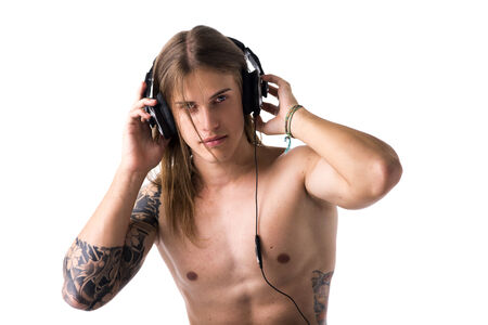 Muscular young man shirtless, listening to music on headphones isolated on whiteの写真素材