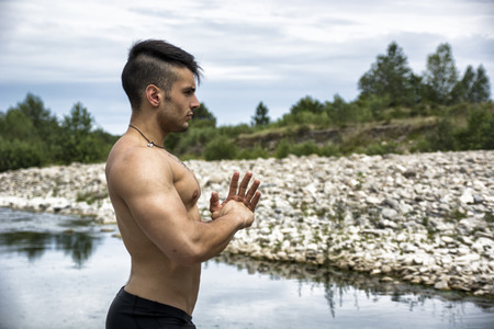 Muscular shirtless young man outdoor near river or lake, concentrated and focussed. Profile shotの写真素材