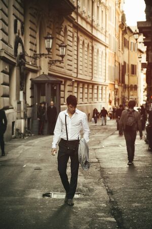 Handsome young man walking in European city street, an alley in Rome, Italyの写真素材