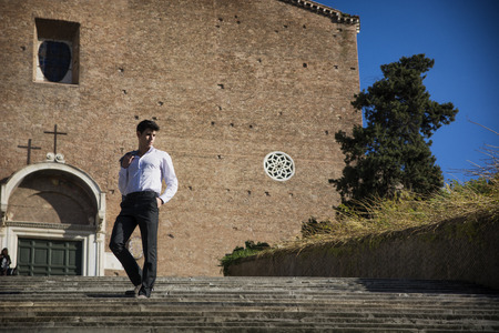 Attractive young man walking down old stair in front of church in Rome, Italy. Large copyspace next to himの写真素材