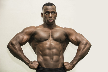 Handsome black male bodybuilder posing in studio showing muscular torso, pecs and back musclesの写真素材