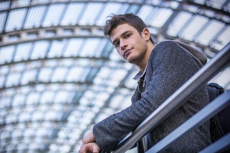 Attractive young man inside modern building, station or airport or office complex