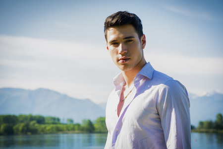 Handsome young man on a lake in a sunny, peaceful day, looking at cameraの写真素材