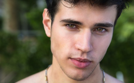 Headshot of handsome attractive young man looking at camera outdoorの写真素材