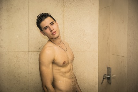 Close up Attractive Young Bare Muscular Young Man Taking Shower, Looking at Cameraの写真素材