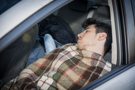 Young handosme man sleeping inside his car, exhausted, tiredの写真素材