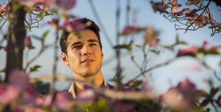 Good looking male model at couuntryside, among flowers, enjoying nature with eyes closedの写真素材