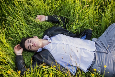 Good looking, fit male model relaxing lying on the grass, with eyes closed, photographed right from aboveの写真素材