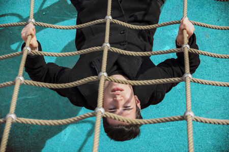 Full length of serious dark haired 20s man wearing black jacket and trousers lying upside-down on...