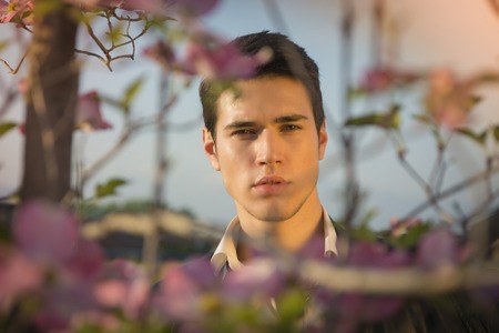 Good looking male model at couuntryside, among flowers, enjoying nature, looking at cameraの写真素材
