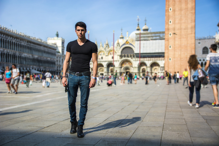 Young Man in San Marco Square in Venice, Italy, wearing black t-shirt and looking at cameraの写真素材