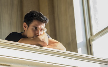 Portrait of Shy Attractive Young Man Leaning on Folded Arms Against Polished Marble Staircase...
