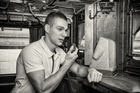 Black and White Retro Close Up of Young Man Speaking into Handheld Radio in Engine of Old Fashioned Train Locomotiveの写真素材